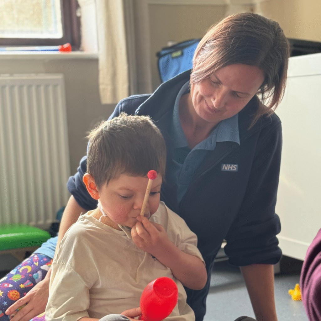 Community Children's nurse sits with a young boy on the floor together